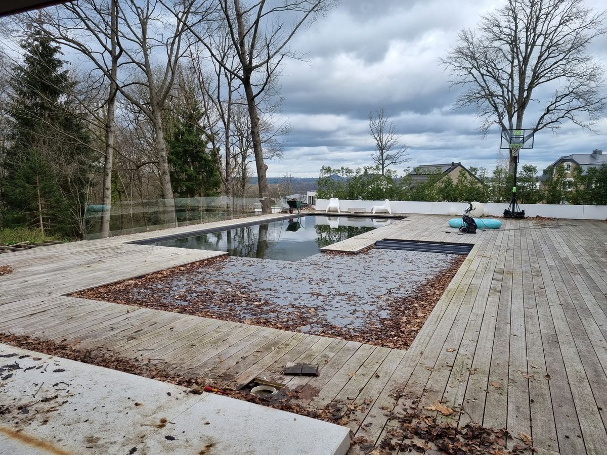 Feuilles mortes accumulées sur la couverture d'une piscine en fin d'hiver