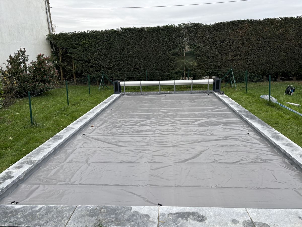 Piscine fermée pour l'hiver sous une bâche d'hivernage grise