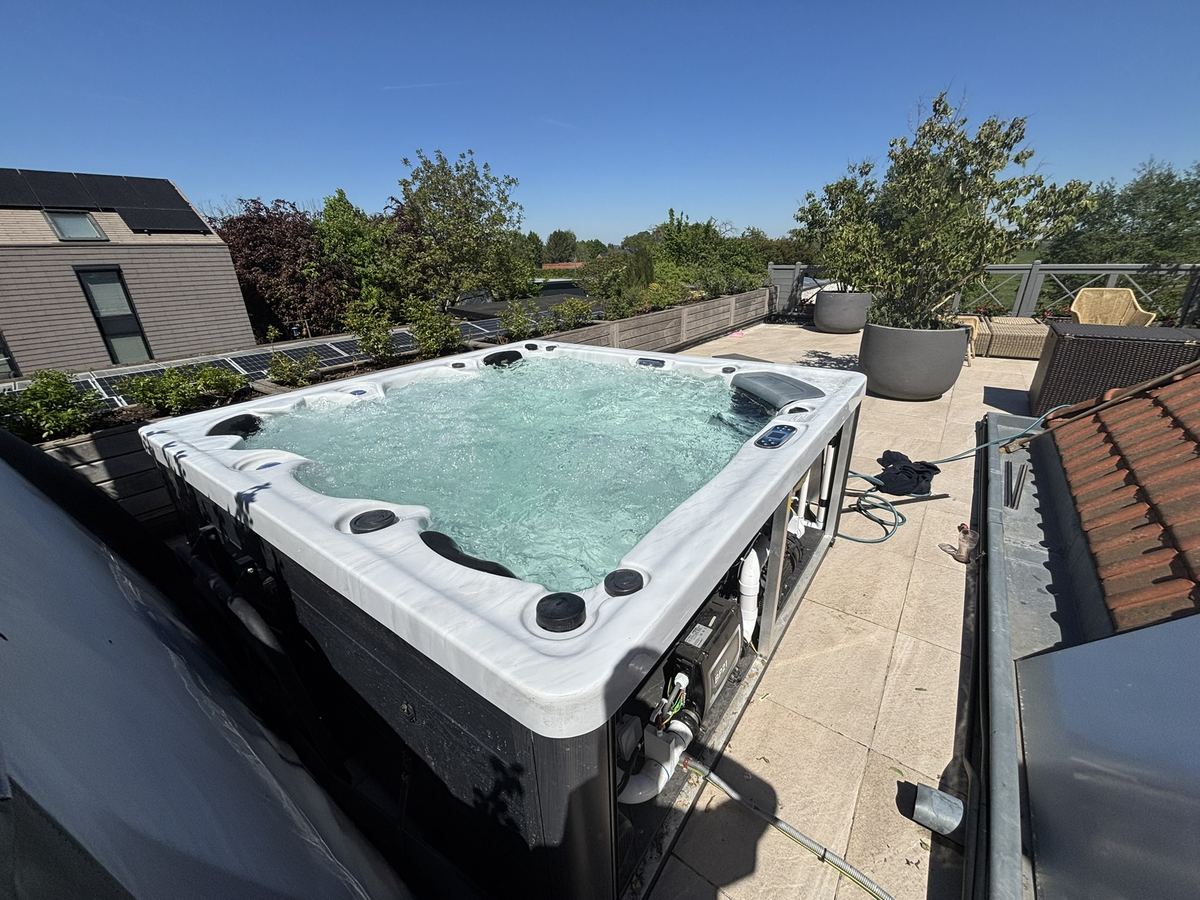 Spa extérieur installé sur une terrasse de toit, entouré de bacs de plantes