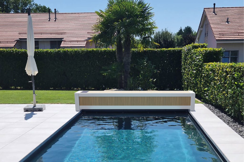 Piscine équipée d'un volet hors-sol avec banc habillé imitation bois